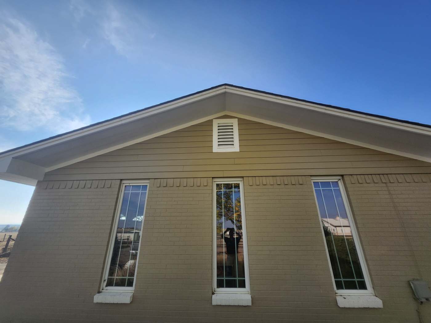 Front gable view of completed James Hardie fiber cement siding installation over painted brick at the Joyful Stables property in Berthoud, Colorado